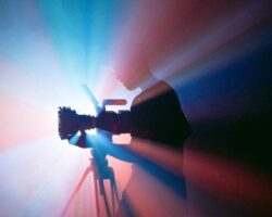 Silhouette eines Kameramanns mit Filmkamera vor farbigem Licht