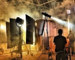 Filmset mit Scheinwerfern, Nebel und sichtbarer Crew in einer Halle