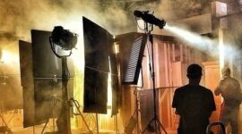 Filmset mit Scheinwerfern, Nebel und sichtbarer Crew in einer Halle