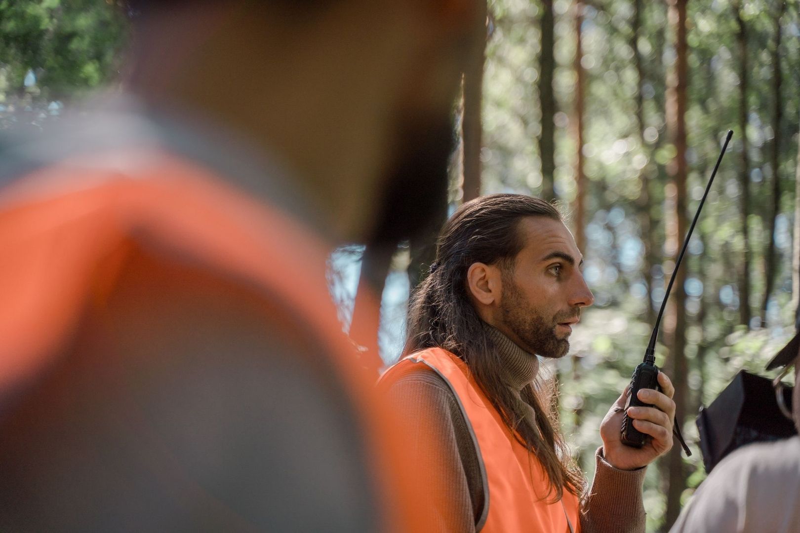 Filmteam-Mitglied mit Funkgerät bei Dreharbeiten im Wald